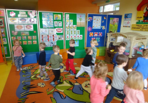 Dzieci spacerują z szablonem zębów w dłoni w sali.